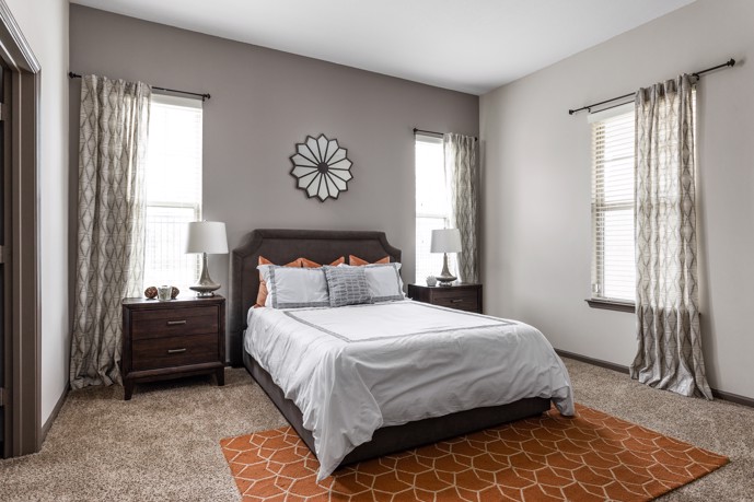 Bedroom adorned with three windows, plush carpet flooring, and convenient doorway access.
